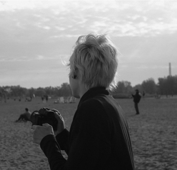 Black and white portrait of Daniela Obando holding a camera on a beach